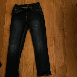 Mörkblå jeans från Lee - Säljer ett par mörkblå jeans från Lee i bra skick. De har en klassisk straight passform och är perfekta för vardagsbruk. Jeansen har en snygg tvätt med lätt slitna detaljer som ger dem en cool look. Perfekta för höst och vår!