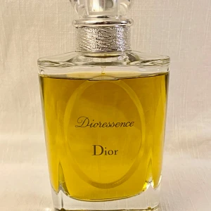 Dioressence Eau de Toilette från Dior - Säljer en elegant flaska Dioressence Eau de Toilette från Dior. Doften är varm och kryddig med inslag av patchouli, kanel och ros. Flaskan är stilren med en klar design & transparent kork .Perfekt för den som älskar klassiska och tidlösa dofter. Ett spray räcker! Nypris 1560kr