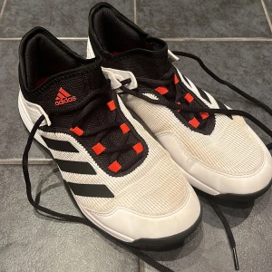 Adidas (Adizero Ubersonic) sneakers  - Säljer ett par Adidas sneakers i svart och vitt med coola röda detaljer. Skorna har snörning och är i mycket bra skick, lite gulnat i tyget och någon fläck som kan gå att tvätta bort. Storlek 38.