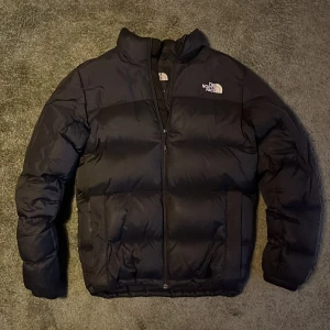 Svart pufferjacka från The North Face - Säljer en svart pufferjacka från The North Face i mycket bra skick. Jackan är fodrad med dun och  är perfekt för kalla vinterdagar. Storlek S men passar M också. Hör av dig vid fler funderingar. Priset kan diskuteras.