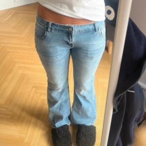 Ljusblå bootcut jeans - Säljer ett par snygga ljusblå bootcut jeans i bra skick. De är lågmidjade och har en klassisk femficksdesign med knapp och dragkedja fram. Perfekta för en avslappnad vardagslook eller en utekväll. Passar bra till både sneakers och klackar! Passar S också!