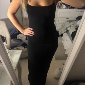 Svart långklänning - Säljer en elegant svart långklänning i tight passform. Perfekt för festliga tillfällen. Klänningen är axelbandslös och har en stilren design som framhäver figuren. Passar utmärkt för både höst och vinter.