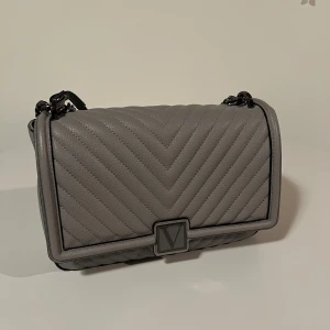 Grå Viktoria secret axelväska - Säljer en snygg grå axelväska med kedjeaxelrem från Victoria’s Secret . Mellan storlek passar perfekt till allting. Helt ny fick den i present❤️