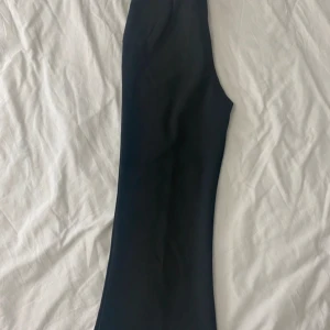 Svarta kostymbyxor - Snygga svarta kostymbyxor i mycket bra skick. De har en klassisk design med hög midja och en rak passform som ger en stilren look. Perfekta för både kontoret och festligare tillfällen. Materialet känns bekvämt och av hög kvalitet.
