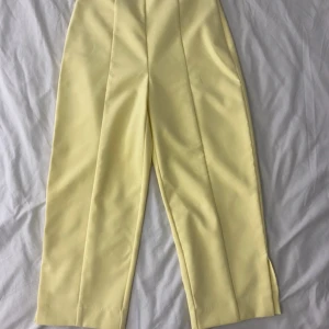 Gula kostymbyxor - Snygga gula kostymbyxor i ett elegant och stilrent snitt. De är högmidjade och har en rak passform som ger en klassisk look. Perfekta för både kontoret och festliga tillfällen. Materialet känns bekvämt och lyxigt. Ett måste för garderoben!