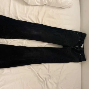 Svarta low waist bootcut jeansbyxor - Säljer ett par svarta jeansbyxor i bra skick. De har en klassisk design med knappar och dragkedja framtill. Perfekta för både vardag och fest💘