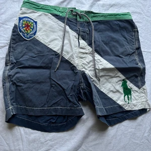 Badshorts från Polo Ralph Lauren - Snygga badshorts från Polo Ralph Lauren i blått, vitt och grönt. De har en cool snörning i midjan och ett broderat märke på framsidan. Perfekta för sommaren och stranden!