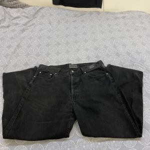 Svarta jeans från Versace Jeans Couture - Säljer ett par snygga svarta jeans från Versace Jeans Couture. De har en klassisk femficksdesign och en stilren look med märkets logga på knappen och bakfickan. Perfekta för både vardag och fest!