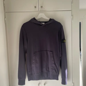 Mörkblå hoodie från Stone Island Junior - Säljer en snygg mörkblå hoodie från Stone Island Junior. Den har en klassisk design med lång ärm och en praktisk ficka framtill. Märkets ikoniska logga sitter på ärmen. Perfekt för både vardag och chill.