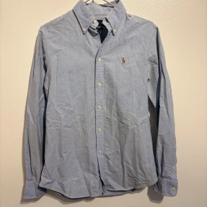 Ralph Lauren skjorta - Säljer en snygg blå skjorta från Ralph Lauren i storlek S. Skjortan har en klassisk design med knappar och en broderad logga på bröstet. Perfekt för både vardag och fest! 💙