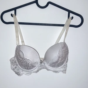 Vit spets-bh - Säljer en elegant vit bh med spetsdetaljer. Den har justerbara axelband och en fin spetskant. Perfekt för att känna sig extra fin till vardags eller fest. Observera att det finns en liten fläck på insidan av bandet.