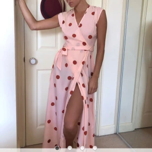 Rosa omlottklänning med prickar - Fin omlottklänning i tunnt material. Perfekt för sommarfester eller utlandsresan. Näst intill oanvänd. 