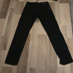 Svarta jeans - Säljer ett par svarta jeansbyxor i bra skick. De har en klassisk design med fem fickor och knappgylf. Perfekta för både vardag och fest! Storlek: W26 L 32 passar 165-175 Skick 8/10