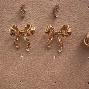 Guldiga rosettörhängen - Superfina guldiga örhängen i form av rosetter. Perfekta för att ge en söt och elegant touch till din outfit. De är i nytt skick och passar både till vardag och fest. Rosetterna är detaljerade och glänsande, vilket gör dem till ett blickfång.