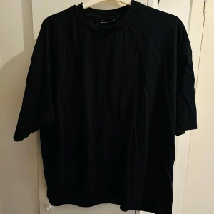 Svart t-shirt med japanskt tryck från ASOS DESIGN - Säljer en svart t-shirt från ASOS DESIGN i storlek M. Den har ett coolt japanskt tryck med texten 'New Season' och ett blommönster i rosa och grått. Perfekt för en avslappnad stil eller en utekväll. T-shirten är i bra skick och gjord av mjukt material.