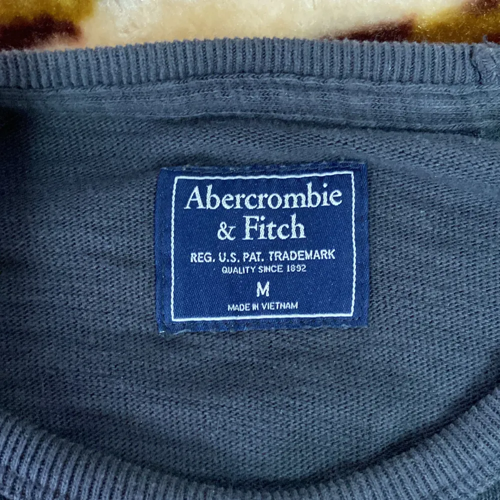 Säljer en snygg grå långärmad tröja från Abercrombie & Fitch. Den har ett coolt tryck i rött på bröstet. Perfekt för höst och vinter, och den är superbekväm att ha på sig. Passar både till vardags och chillkvällar. 🖤. Neuletakit & Villapaidat.