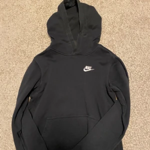 Nike hoodie - Säljer min svarta Nike hoodie som för att den är för liten. Skicket är 9/10 och hoodien är knappt använd. Hoodien är storlek L i barnstorlek