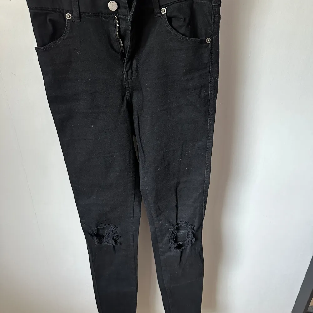 Svarta jeans med hål på knäna. Storlek S, normal i storleken, dock inte jätte stretchiga. De är använda fåtal gånger då de drar till sig mycket hår (om man har hund/katt). I övrigt snygga byxor på. . Jeans & Byxor.