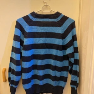 Blå och svart randig tröja - Säljer en snygg blå och svart randig tröja med långa ärmar. Perfekt för höst och vinter. Den har en ribbad krage och muddar som ger en skön passform. Tröjan är i bra skick och redo för nya äventyr! Tröjan är i storlek 146cm för barn!!