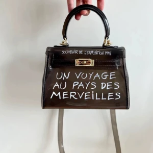 Un Voyage Au Pays Des Merveilles väska - Väskan är helt i nyskick och väldigt cool. Går att ta av det längre bandet också om man så önskar! Köpt nypris för cirka 600kr från en dansk butik 💞