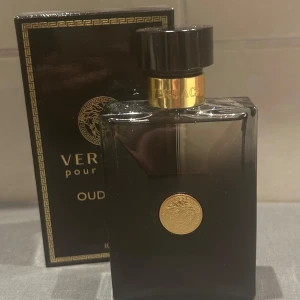 Versace Pour Homme Oud Noir - Elegant och mystisk parfym från Versace, Pour Homme Oud Noir, i en stilren svart flaska med guldiga detaljer. Doften är intensiv och maskulin, perfekt för den som vill utstråla självsäkerhet. Flaskan rymmer 100 ml Eau de Parfum. Aldrig använd😊