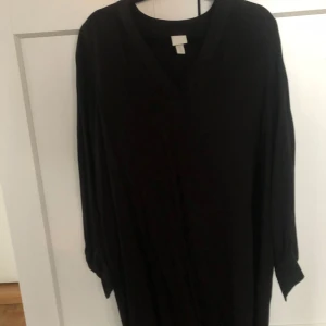 Svart Tunika med v-ringning - Elegant svart tunika med v-ringad hals och långa ärmar. Perfekt för en stilren look.