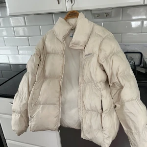 Vit pufferjacka från Columbia - Säljer en vit pufferjacka från Columbia med dragkedja. Jackan är perfekt för kyliga dagar och har en hög krage för extra värme. Använt den hela förra vintern och därför har lite smink fläckar kommit på den. Den kan dock tas bort om man orkar med det haha.