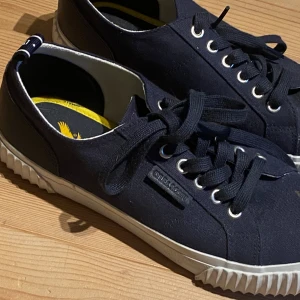 Mörkblå sneakers från Lyle & Scott - Väldigt snygga mörkblå sneakers från Lyle & Scott som är i liknande modell som samba adidas. Varan är helt oanvänd bara gått i inomhus. Hör av dig om du har frågor❤️