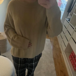 Beige stickad tröja - Mysig beige stickad tröja med ribbade detaljer. Perfekt för kyligare dagar med sin avslappnade passform och långa ärmar.