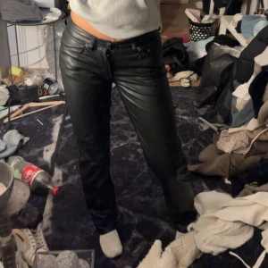 Svarta skinnbyxor - Snygga svarta skinnbyxor med låg midja. Byxorna har en klassisk design med fickor bak och dragkedja fram. Perfekta för en stilren look.