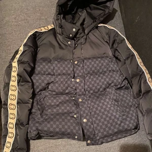 Gucci jacka! - Snygg svart pufferjacka från Gucci, i väldigt bra skick då den endast är använd en gång, är i storlek M men passar även S! Den är också väldigt skön och varm nu till vintern!