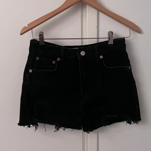 Svarta jeansshorts med fransar - Snygga svarta jeansshorts med fransiga kanter och klassisk femficksdesign. Perfekta för en avslappnad stil. De har en knapp och dragkedja framtill.