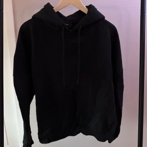 Svart hoodie från LXA - Svart hoodie från LXA med tryck på baksidan. Den har en klassisk design med huva. Perfekt för en avslappnad stil.