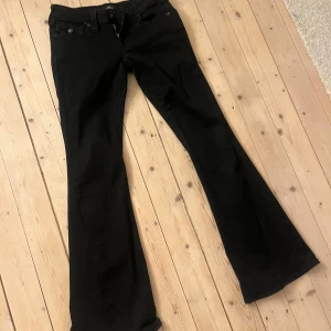 Svarta bootcut jeans från True Religion - Snygga svarta bootcut jeans från True Religion med klassisk femficksdesign och knappdetalj på bakfickan. Perfekta för en stilren look. Modell Joey Low Rise flare storlek 34. Nypris 1290. 