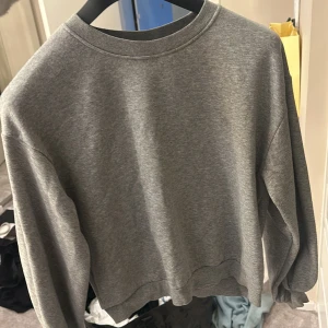 Grå sweatshirt från Vero Moda - Säljer en grå sweatshirt från Vero Moda. Tröjan har en klassisk rund hals och långa ärmar. Perfekt för en avslappnad stil.