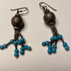 Örhängen med turkosa pärlor - Unika vintage  örhängen med antik stil, från USA dekorerade med turkosa pärlor och detaljerade metallinslag. Perfekta för att ge en bohemisk touch till din stil.