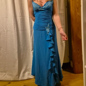 Blå långklänning / balklänning - Elegant blå långklänning med v-ringad urringning och vackra spetsdetaljer vid bysten. Klänningen är perfekt för t ex studentbal eller sittning! Vackert chiffon och satin tyg! Vintage från 90 tal