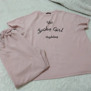 Rosa t-shirt med text - Säljer en rosa t-shirt med texten 'Not Lucky Girl Fighting' i svart. T-shirten har en avslappnad passform och korta ärmar. Perfekt för en casual look.