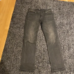 Grå/svarta jeans från Neuw - Säljer ett par grå jeans från Neuw i modellen Lou Straight. De har en klassisk femficksdesign och en rak passform. Perfekta för en med lite relax still 