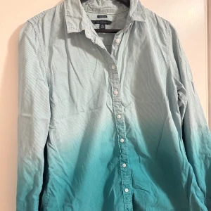 Tommy  Hilfiger - Snygg långärmad skjorta från Tommy  Hilfiger i en grön- och vitrandig design. Skjortan har knappar framtill och en klassisk krage. Perfekt för en stilren look.