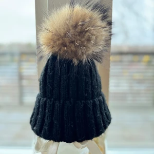 Svart ribbad mössa med pälsboll - Snygg svart ribbad mössa med en stor fejkpälsboll. Stilren design som passar till det mesta! Vuxen One size. Nypris 499:-. Frakt ingår!