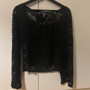 Svart spetsblus från Veromoda - Elegant svart spetsblus från Veromoda med långa ärmar. Perfekt för en stilfull look med sitt genombrutna spetsmönster. Passar utmärkt till både vardag och festliga tillfällen. Den är knappt använd då den är förstor för mig. In princip ny utan prislapp. Den är lite liten i storlekarna!!