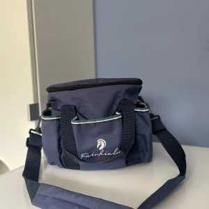 Blå axelväska från Fairfields - Jag säljer min ryktväska med borstar då de inte längre kommer till någon användning,  de är sparsamt använda och borstarna är välskötta. Detta är ett perfekt kit för kanske dig eller ditt barn som vill ha en egen ryktväska med borstar. Med dessa borstar så kommer man att definitivt få rent hästen!  De borstar som ingår är: piggborste, rotborste, man- och svansborste, hovkrats, pannborste, ryktborste och ryktskrapa.