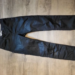 Svarta glansiga jeans - Svarta glansiga jeans. De är i modellen skinny jeans med lite strech. De är som vanligt jeans material med glansigt lager. I bra skick. 