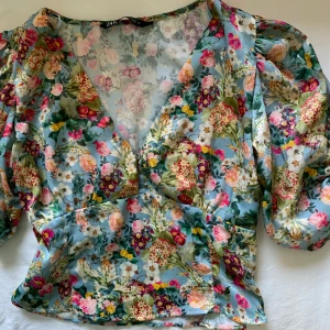 Blommig blus - Superfin blommig blus från Zara med puffärmar och knappstängning framtill. Säljer då den tyvärr aldrig kom till användning . I mycket bra skick! Axelbredd 33cm och längd 44 cm.