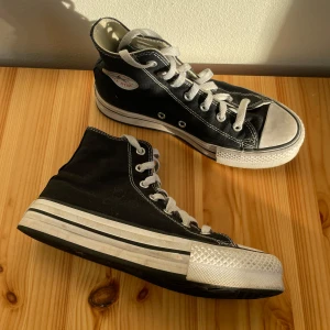 Svarta Converse - Säljer ett par klassiska svarta Converse sneakers med hög snörning och vit sula. De är i modellen med något högre sula än klassiska chuck, men inte den höga platån. Köpte förra våren och är sparsamt använda så i gott skick! 