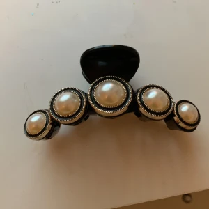 Hårklämma med pärldetaljer - Elegant hårklämma i svart med stora pärldetaljer och guldfärgade kanter. Perfekt för att ge en stilfull touch till din frisyr.säljer pg av att jag har för mycket hår o den passar ej 