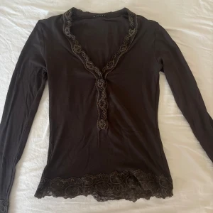 Söt blus från Sisley - Söt blus/topp från Sisley, står inte storlek men passar mig som är XS/S. Spets på ärmarna och kragen, knappar längst hela kragen. Jättefint skick!