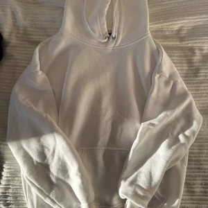 Vit hoodie från BikBok - Säljer en stilren vit hoodie från BikBok i storlek S. Den har en klassisk design med en stor ficka framtill och justerbar huva med dragsko. Perfekt för en avslappnad look.
