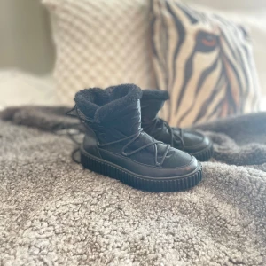 Svarta Inukii liknande skor med pälsfoder - Säljer ett par svarta vinterboots i glansigt material med mysigt pälsfoder. Perfekta en kall vinter. Använda max 5 gånger